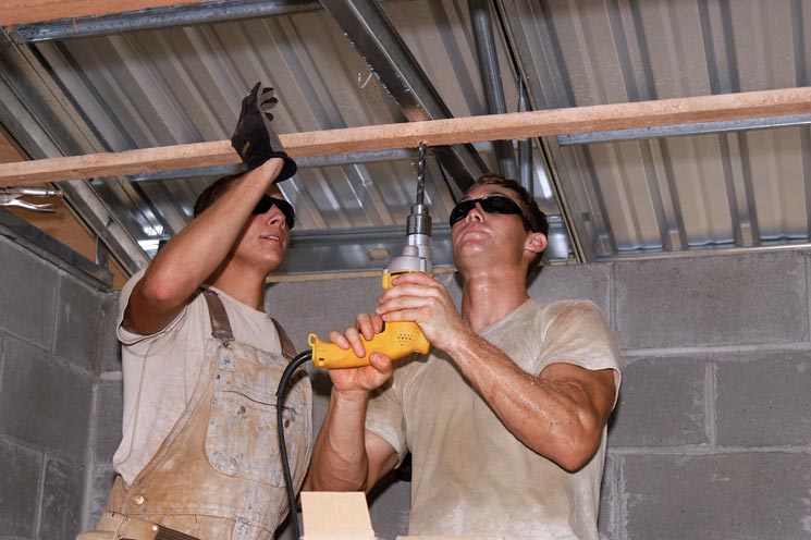Bauarbeiter befestigen Holzleiste mit Bohrer